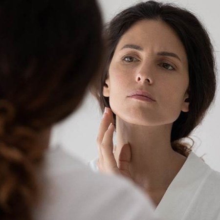 Concerned woman observing herself in the mirror