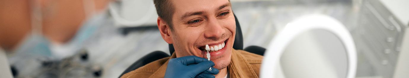 a dentist matching the color of a patient’s teeth