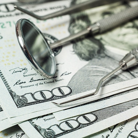 dental instruments sitting on a stack of money