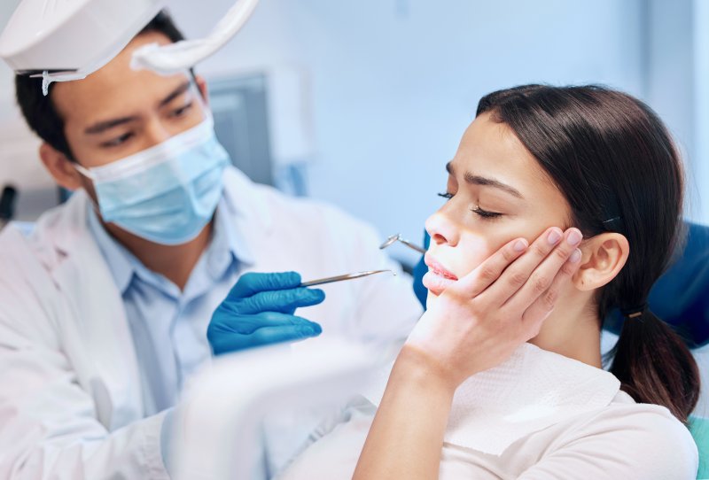 A dentist helping a woman suffering from a toothache