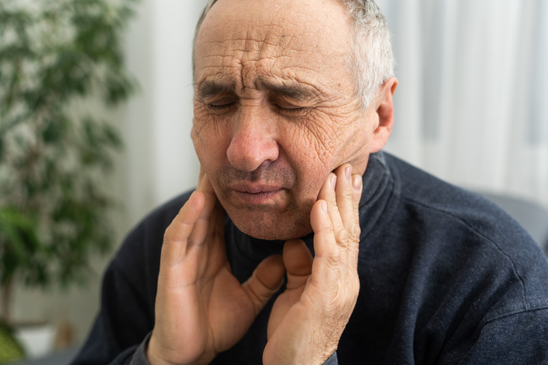 Patient rubbing their jaw due to TMJ disorder